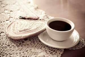 branco copo do Preto café e uma doce amanteigado bolacha em a mesa foto