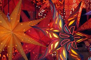 luzes na escuridão. estrelas tradicionais vermelhas e douradas como lanternas de Natal no mercado. foto