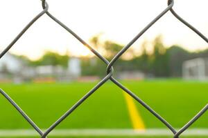 uma futebol campo Visão a partir de lado de fora a cerca, concentrando em a cerca. depois de alguns Editar% s. foto