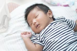 adorável asiático dormindo, bebê pequeno sono saudável com cobertor branco de lã quente em casa foto