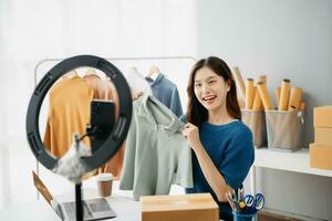 ásia senhora blogueiro mostrando roupas dentro frente do a Câmera para gravação vlog vídeo viver transmissão às dela fazer compras. foto