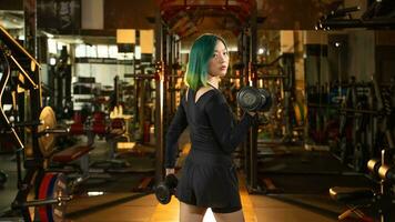 desportivo mulher faz a exercícios com halteres às academia. foto do muscular mulher dentro roupa de esporte. força e motivação.