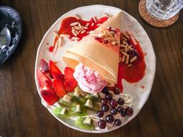 deliciosos crepes caseiros saborosos com sorvete de morango, crepes recheados com morangos, kiwi, uva foto