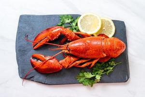 lagosta vermelha com vegetais e limão no prato de ardósia preta