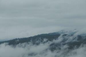 lindo panorâmico Visão do névoa e nuvens dentro distante camadas montanhas alcance com azul céu dentro manhã foto