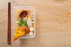 macarrão com bola de peixe e carne de porco picada na caixa de entrega - comida asiática foto