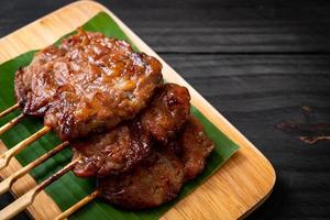 Carne de porco grelhado no espeto com arroz branco pegajoso - comida de rua tailandesa local foto