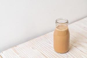 café com leite em garrafa no fundo de madeira