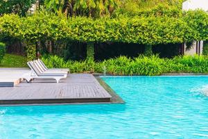 cadeiras de piscina ao redor de piscinas em hotel resort - conceito de feriados e férias foto