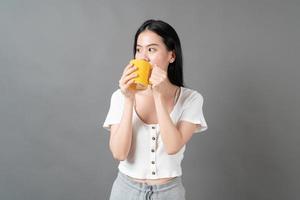 jovem mulher asiática com um rosto feliz e uma mão segurando uma xícara de café foto