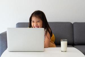 uma jovem asiática usando o computador para aprender em casa como protocolo de distanciamento social durante covid-19 ou pandemia de coronavírus. conceito de ensino em casa