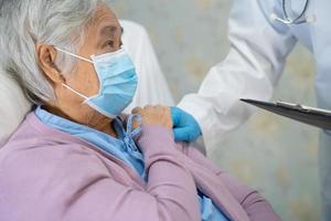médico usando o estetoscópio para verificar o paciente asiático sênior ou idosa senhora usando uma máscara facial no hospital para proteger a infecção covid-19 coronavírus. foto