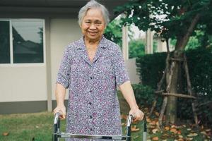 Paciente mulher idosa asiática sênior ou idosa caminhar com andador no parque em casa, conceito médico forte e saudável foto