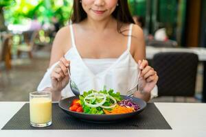 jovem mulher comendo saudável salada às restaurante, saudável estilo de vida e dieta conceito foto