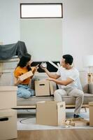 feliz ásia jovem atraente casal homem e mulher com grande caixas comovente para dentro uma Novo casa, Novo apartamento para casal a Novo lar, comovente casa. foto