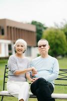 ásia Senior casal tendo uma Boa tempo. elas rindo e sorridente enquanto sentado ao ar livre às a parque. adorável Senior casal foto