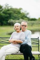 ásia Senior casal tendo uma Boa tempo. elas rindo e sorridente enquanto sentado ao ar livre às a parque. adorável Senior casal foto