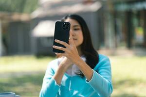 lindo ásia mulher falando em inteligente telefone ter conversação conectados virtual bate-papo vídeo ligar com amigos. estilo de vida menina vlog vídeo em social meios de comunicação foto