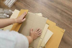 casa reciclar eco zero desperdício conceito homem usando reciclar papel caixa. empilhamento Castanho cartão caixa eco amigáveis embalagem fez do reciclável cru materiais. foto