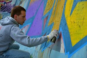 kharkov, ucrânia - 27 de maio de 2017 festival de artes de rua. jovens desenham grafite em paredes de concreto antigas no centro da cidade. o processo de pintura em paredes com latas de aerossol foto