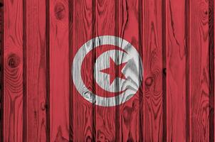 bandeira da tunísia retratada em cores brilhantes de tinta na parede de madeira velha. banner texturizado em fundo áspero foto