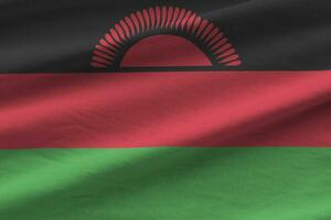 bandeira do malawi com grandes dobras acenando de perto sob a luz do estúdio dentro de casa. os símbolos oficiais e cores no banner foto