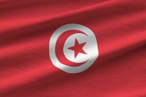 bandeira da tunísia com grandes dobras acenando de perto sob a luz do estúdio dentro de casa. os símbolos oficiais e cores no banner foto