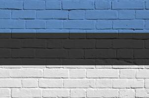 Estônia bandeira retratado dentro pintura cores em velho tijolo muro. texturizado bandeira em grande tijolo parede alvenaria fundo foto
