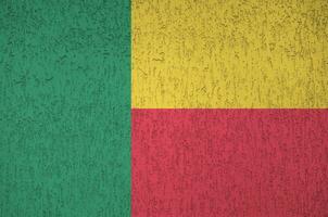 bandeira do benin retratada em cores brilhantes de tinta na parede de reboco em relevo antigo. banner texturizado em fundo áspero foto