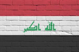 Iraque bandeira retratado dentro pintura cores em velho tijolo muro. texturizado bandeira em grande tijolo parede alvenaria fundo foto