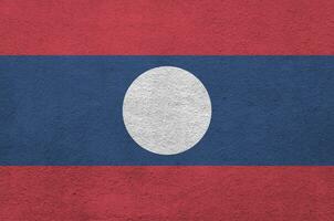 bandeira do laos retratada em cores brilhantes de tinta na parede de reboco em relevo antigo. banner texturizado em fundo áspero foto