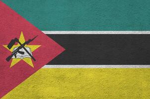 bandeira de moçambique retratada em cores de tinta brilhante na parede de reboco em relevo antigo. banner texturizado em fundo áspero foto