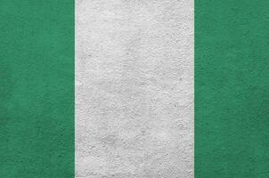 bandeira da nigéria retratada em cores de tinta brilhante na parede de reboco em relevo antigo. banner texturizado em fundo áspero foto