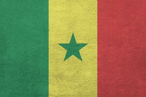 bandeira do senegal retratada em cores de tinta brilhante na parede de reboco em relevo antigo. banner texturizado em fundo áspero foto