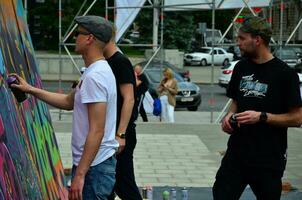 kharkov, ucrânia - 27 de maio de 2017 festival de artes de rua. jovens desenham grafite em paredes de madeira portáteis no centro da cidade. o processo de pintura em paredes com latas de aerossol foto