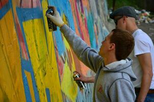 kharkov, ucrânia - 27 de maio de 2017 festival de artes de rua. jovens desenham grafite em paredes de concreto antigas no centro da cidade. o processo de pintura em paredes com latas de aerossol foto