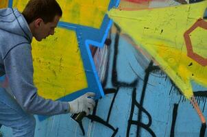 kharkov, ucrânia - 27 de maio de 2017 festival de artes de rua. jovens desenham grafite em paredes de concreto antigas no centro da cidade. o processo de pintura em paredes com latas de aerossol foto