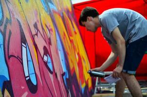 kharkov, ucrânia - 27 de maio de 2017 festival de artes de rua. jovens desenham grafite em paredes de madeira portáteis no centro da cidade. o processo de pintura em paredes com latas de aerossol foto