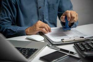 homem estampagem aprovação do trabalhos finança bancário ou investimento marketing documentos .para oficial e legal contratos e acordos, financeiro declarações, investimento contratos em escrivaninha. foto