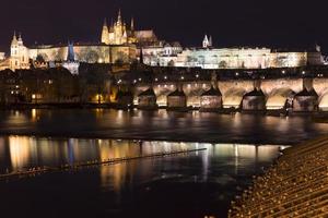 noite colorida com neve natal praga menor cidade com castelo gótico e ponte charles, república checa foto