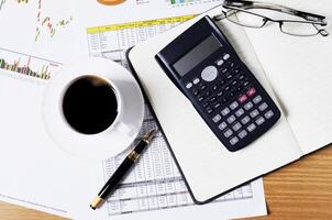 conceito de negócio com calculadora e caneta-tinteiro e xícara de café na mesa de trabalho com documento foto