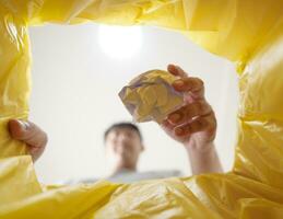 imagem a partir de dentro amarelo reciclando saco do homem jogando esvaziar plástico garrafa dentro reciclando bin casa reciclar eco verde zero conceito. foto