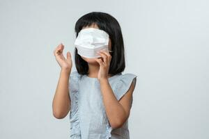 retrato do engraçado ásia menina criança com protetora face mascarar. conceito do criança indo costas para escola e Novo normal estilo de vida foto