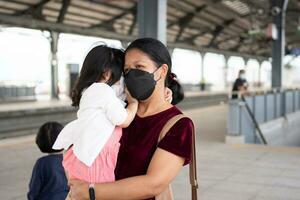 pequeno menina e mãe com cirúrgico mascarar face proteção gripe e vírus surto dentro público transporte. conceito do Novo normal estilo de vida, usando público transporte para viagem para escola foto