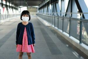 menina com máscara cirúrgica proteção facial contra gripe e surto de vírus em transporte público skytrain ou metrô. conceito de novo estilo de vida normal, usando o transporte público para viajar para a escola. foto