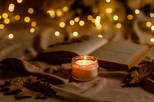 uma vela acesa em uma mesa de madeira em frente a um livro a meio mastro foto