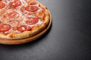 saborosa pizza fresca de forno com tomate, queijo e manjericão em um fundo de concreto foto