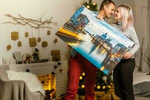feliz jovem mulher e dela namorado segurando tela de pintura enquanto comovente para dentro Novo casa foto