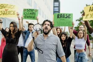 homem gritando através megafone enquanto protestando com pessoas em rua foto