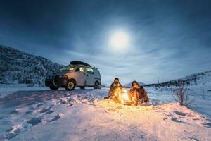 campistas às acampamento fogo dentro inverno panorama dentro polar noite, Kilpisjaervi, enontekioe, Finlândia foto